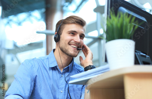 Smiling friendly handsome young male call centre operator.