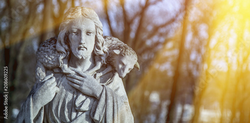 Ancient statue of Jesus Christ is the Good Shepherd with the lost sheep on his shoulders. (Biblical tradition, religion, Christianity, God, faith concept)