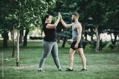 Plus size woman shaking arm of personal trainer