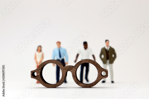 The concept of biased views judged by appearances. Various miniature people standing behind the glasses.