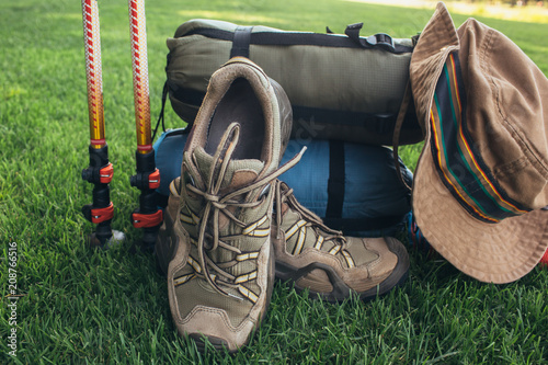 trekking poles, boots, , sleeping bag , hat and other equipment backpacker, on the green grass close-up