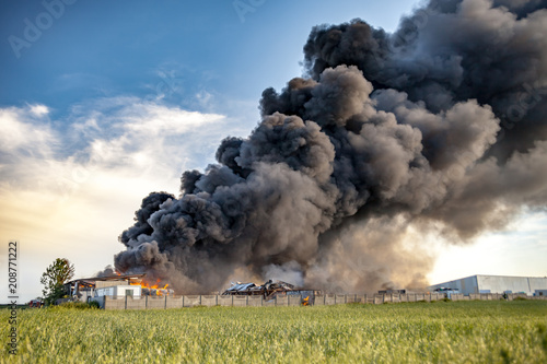 Building fire among fields and huge black smoke cloud
