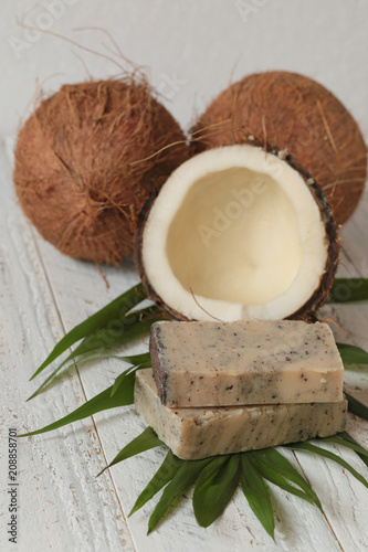 coconut soap.soap with coconut extract. Handmade soap with coconut oil on a palm leaf and coconut in a cut on a shabby wooden background. Organic Natural Cosmetics
