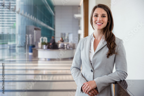Cute commercial business corporate representative woman model brunette smiling in large building hall lobby