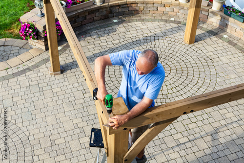Man building a wooden gazebo on a brick patio