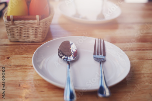 Spoon and fork on empty plate on table in the restaurant