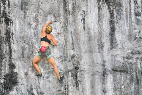 Young woman climbing a cliff without safety equipment on a summer day, copy space