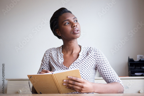 serious young woman thinking and writing in journal