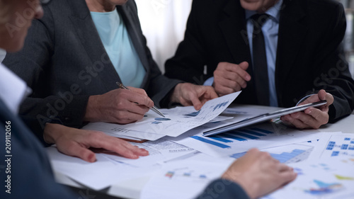 Government officials discussing import and export report diagrams, research