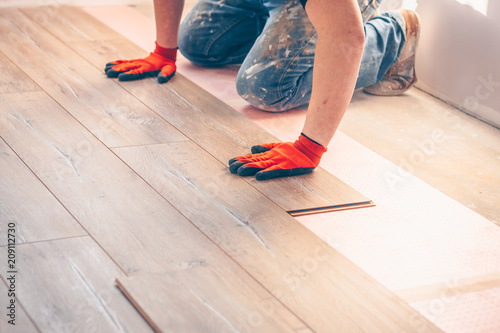 Working with hands installs a laminate board, professional flooring installation