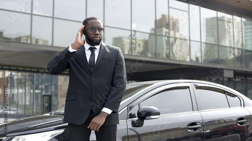 Afro-American security worker listening boss directions in earphones, security