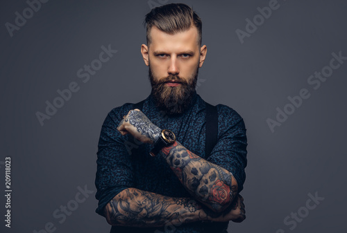 Handsome old-fashioned hipster in shirt and suspenders, pose with crossed arms. Isolated on a dark background.