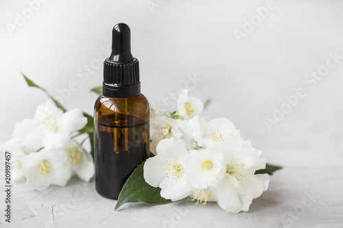 Jasmine essential oil. Bottle of jasmine aromatherapy oil with jasmine flowers