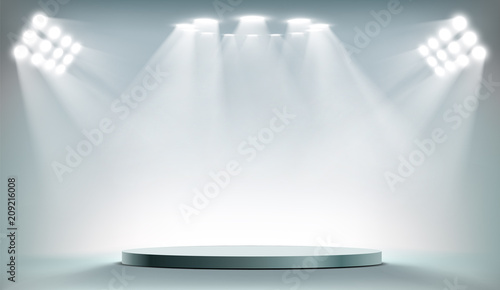 Round podium illuminated by searchlights.