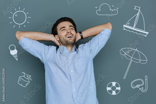 At the beach. Cheerful excited hardworking man feeling happy while being on the beach and enjoying his leisure time