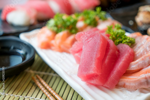 Mixed sliced fish sashimi in white plate. Sashimi Salmon and Tuna set with Tuna, flying fish roe caviar and Foie Gras closeup. Japan restaurant menu