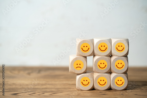 Viele Würfel mit lächelnden Smileys und einer der unzufrieden ist 