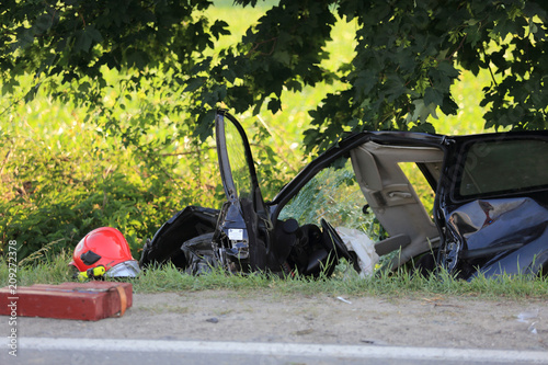 Wypadek drogowy, rozbity samochód leży w rowie.