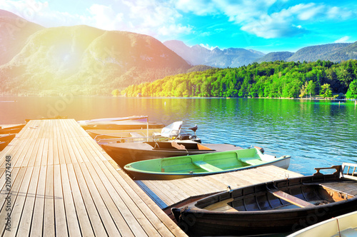 Colorful summer on the Bohinj Lake. Moning sun light in the Triglav National Park, Julian Alps, Slovenia.A pier with boats on a clear crystal water with beautiful nature in background. 