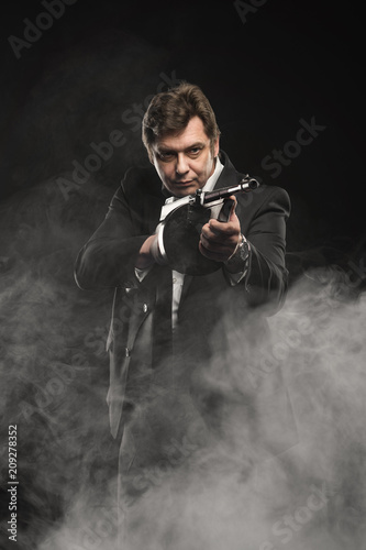 Handsome middle aged man gangster with Thompson machine gun on dark background