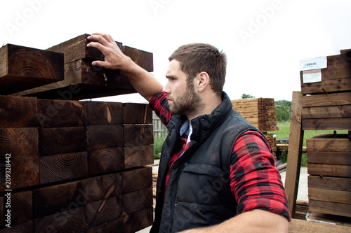 Lumber yard worker, carpenter, choosing, seclecting carrying timber planks