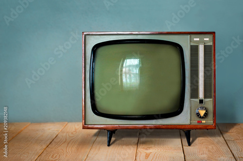 Vintage TV set on wooden table against old blue wall background