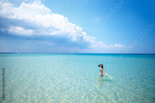 Beautiful happy woman standing in swimsuit in azure sea, vacation concept