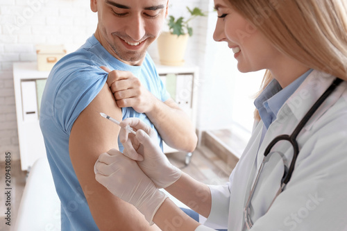 Doctor vaccinating male patient in clinic