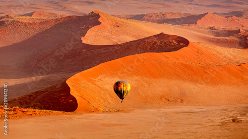 Hot air balloon in flight against orange sand dunes in Sossusvlei Namibia