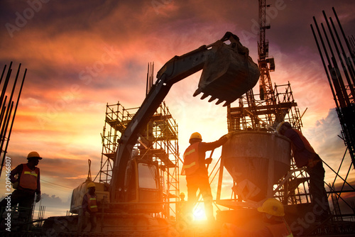 Silhouette Teams of Business Engineers looking for blueprints in construction sites through blurry construction sites at sunset.