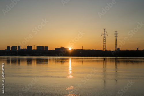 Sunset on the city river. Evening landscape on the river bank