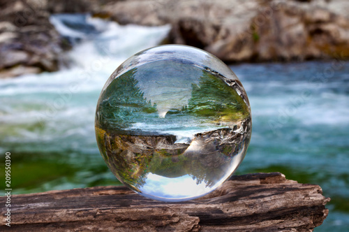 Crystal glass ball sphere reveals waterfall landscape with spherical perspective
