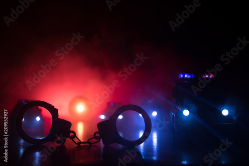 Closed handcuffs on the street pavement at night with police car lights