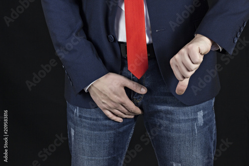 Mens hand holds on the groin and shows the gesture of the finger down, erection