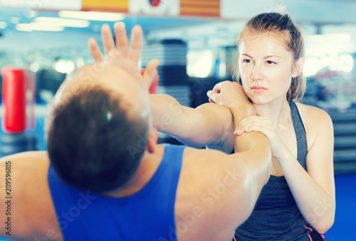 Woman and trainer practicing punches in gym