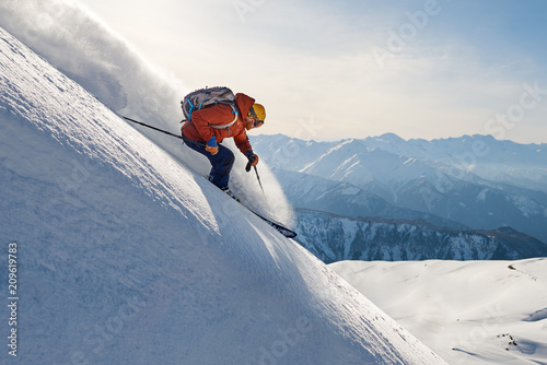 skier rides freeride on powder snow down slope against the backdrop of the mountains
