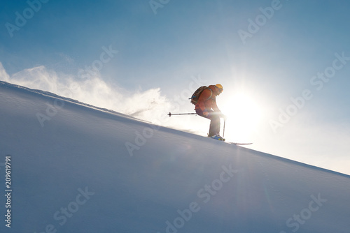 skier rides freeride on powder of snow leaving wave