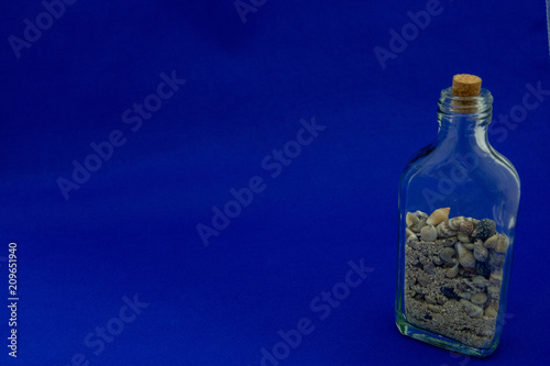 A bottle of sands and shells on the blue background