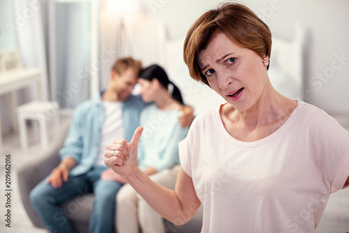 Unhappy mother in law. Cheerless aged woman looking at you while worrying about her son