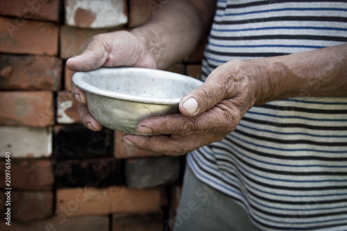 The poor old man's hands hold an empty bowl. The concept of hunger or poverty. Selective focus. Poverty in retirement.Homeless. Alms