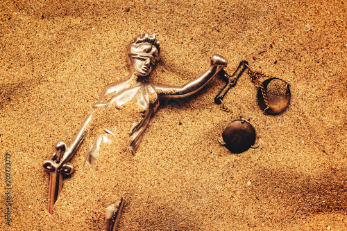 Statue of lady Justice buried in sand