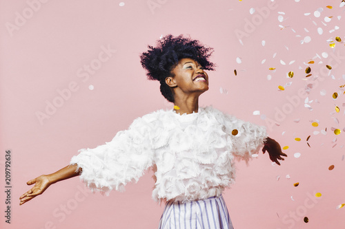 A magical time - Portrait of a very happy girl with arms out, smiling at confetti falling