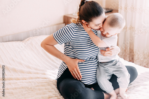 pregnant woman playing and hugging with her second baby