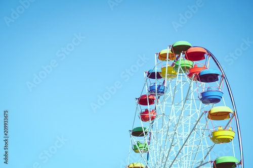 Multicolored Ferris wheel against the blue sky. Toned