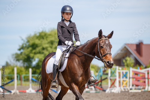 Teenage girl riding bay horse performing dressage test on equestrian competition
