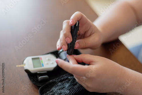 Woman tests her blood sugar using glucose meter