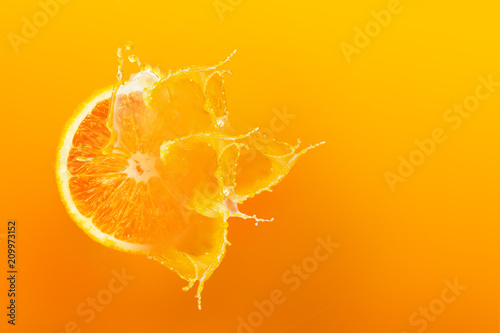 Fresh half slice of ripe orange fruit floation with splash drop on orange juice with copy space