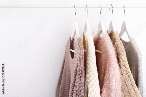 Ciepłe dzianinowe, jesienne, zimowe ubrania wiszące na stojaku, modny trend, pastelowe kolory