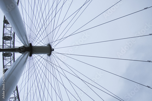 wheel spokes, strings, a fragment of a huge wheel on the cloudy sky background, pillars, columns, modern pendant structure, UK