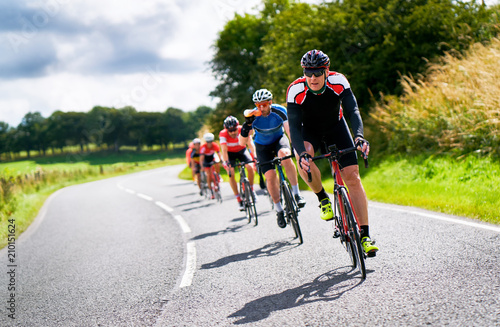 Cyclists racing on country roads on a sunny day in the UK.